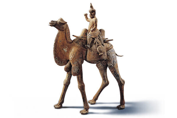 唐代．加彩人物骑驼俑+骆驼俑的体型高大，背上驮负一位头戴高帽的胡人，呈现丝绸之路上行旅往来的风貌。（图四）